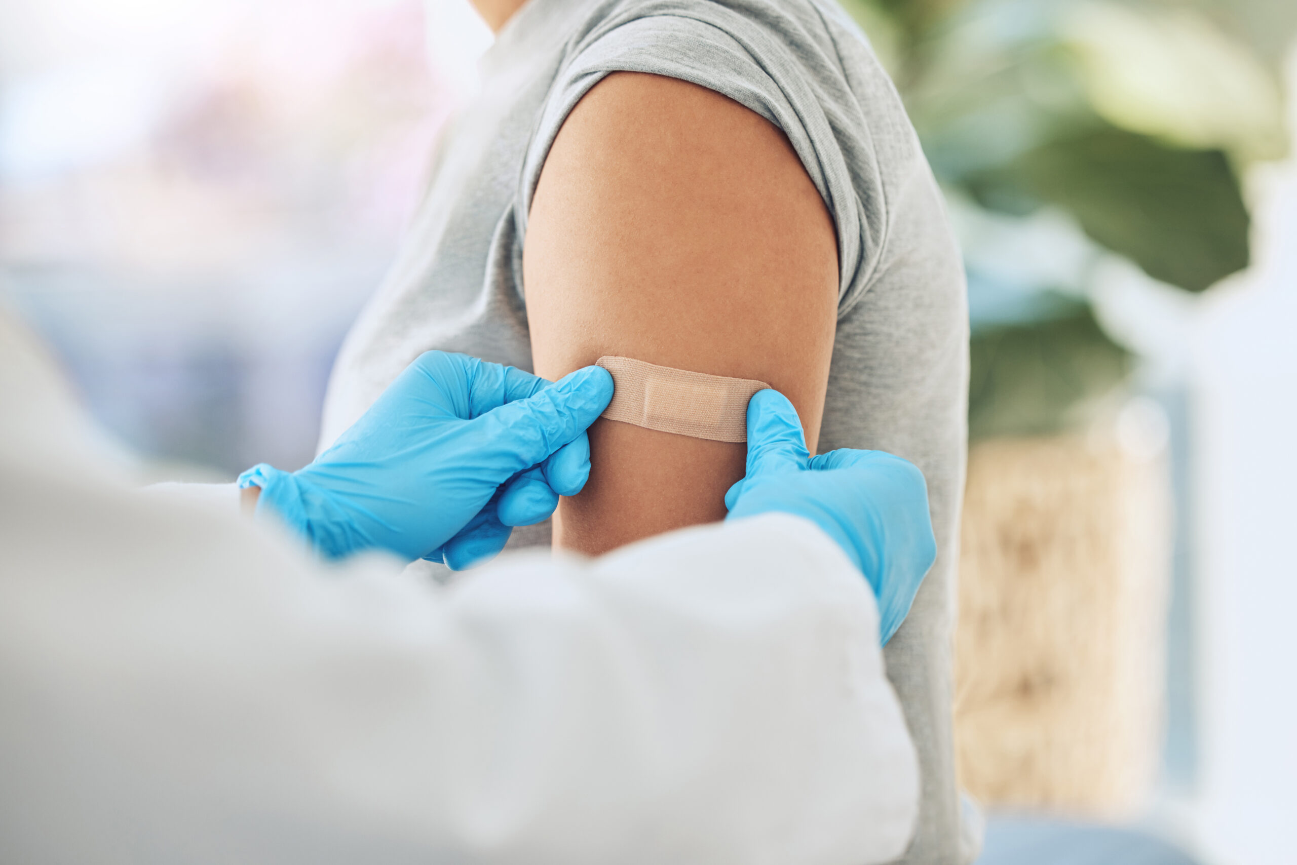 Covid virus vaccination, vaccine and doctor hands with plaster on patient arm in a medical hospital or clinic. Healthcare worker help, trust and safety flu shot antigen for protection against disease.