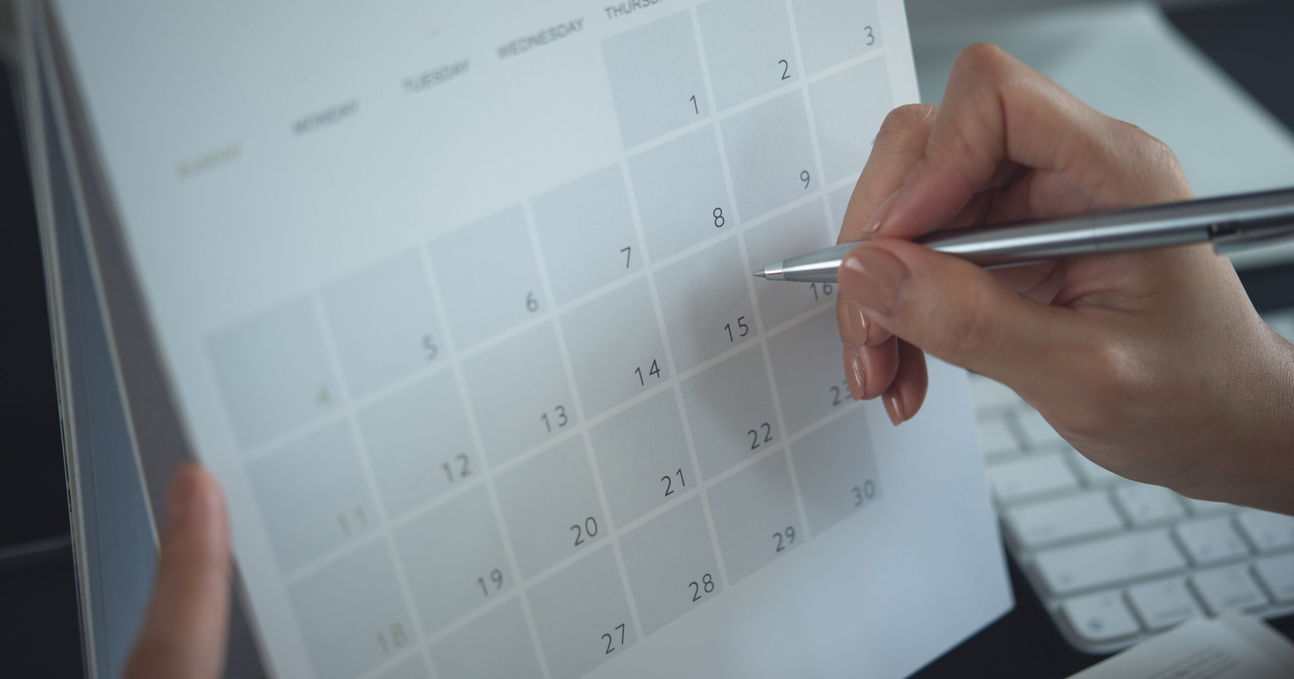 Closeup, woman hand writing on calendar event planner to set timetable organize schedule, event planning for business meeting or vacation plan. Organization and business planning concept.